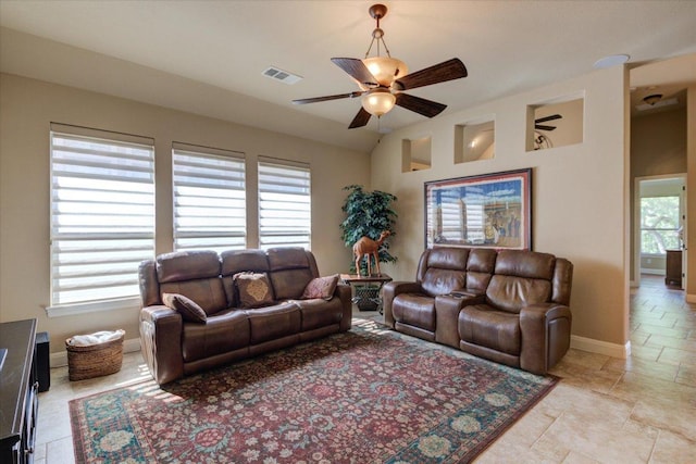 living area featuring ceiling fan, baseboards, and light stone finish floors