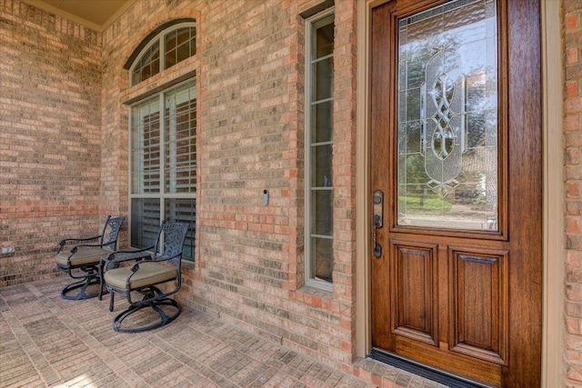 property entrance featuring covered porch and brick siding