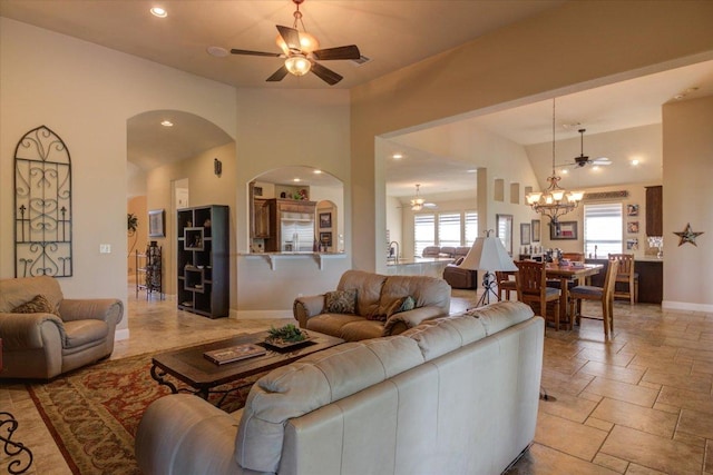 living room featuring a chandelier, ceiling fan, recessed lighting, baseboards, and arched walkways