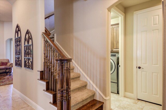 staircase featuring arched walkways, baseboards, and washer / dryer