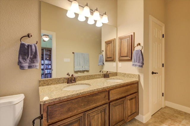 full bathroom featuring toilet, double vanity, and baseboards