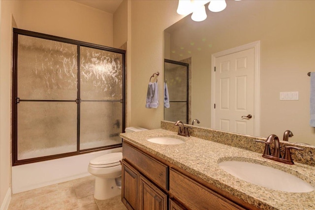 bathroom featuring toilet, bath / shower combo with glass door, double vanity, and tile patterned floors