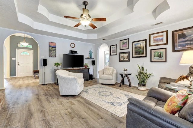 9840 N Live Oak Rd, Salado, TX 76571 - living area featuring arched walkways, a tray ceiling, a ceiling fan, light wood-style flooring, and baseboards