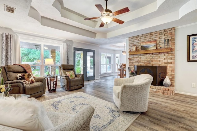 9840 N Live Oak Rd, Salado, TX 76571 - living room with a raised ceiling, baseboards, ceiling fan, wood finished floors, and a brick fireplace