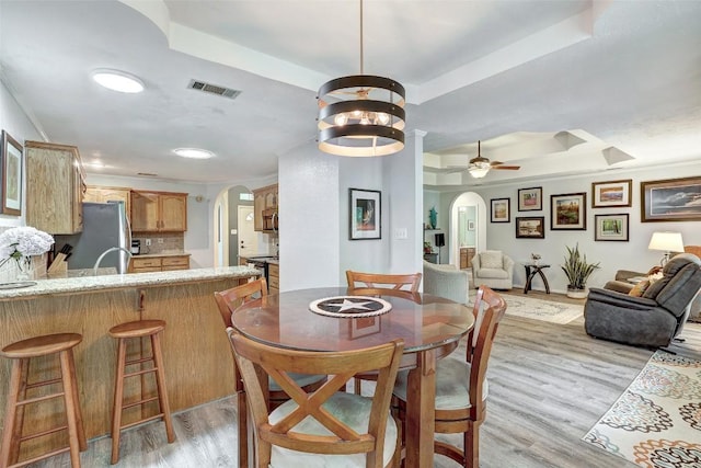 9840 N Live Oak Rd, Salado, TX 76571 - dining area featuring arched walkways, a raised ceiling, ceiling fan, and light wood-type flooring