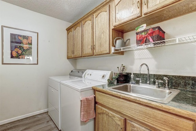 9840 N Live Oak Rd, Salado, TX 76571 - laundry room featuring washing machine and clothes dryer, cabinet space, light wood-type flooring, a textured ceiling, and baseboards