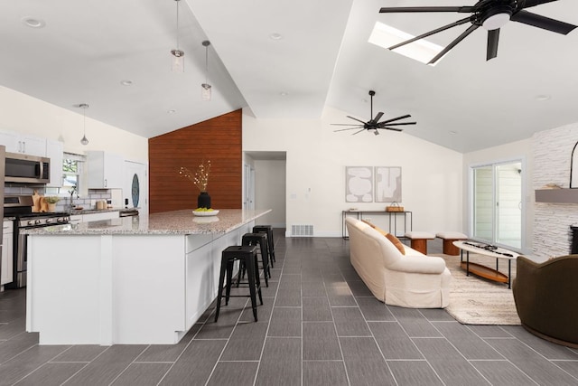 4535 Pack Saddle Pass, Austin, TX 78745 - kitchen with stainless steel appliances, a ceiling fan, white cabinets, open floor plan, and high vaulted ceiling