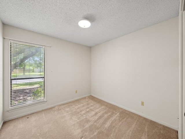 unfurnished room featuring carpet floors, a textured ceiling, and baseboards