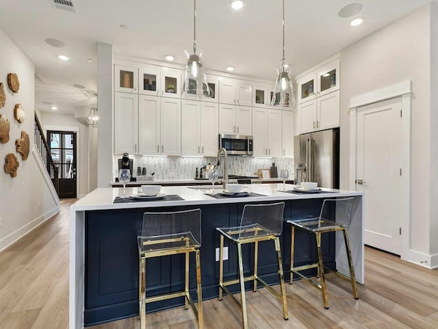 710 Bernese Pass, Austin, TX 78745 - kitchen with stainless steel appliances, white cabinetry, recessed lighting, tasteful backsplash, and light wood-style flooring