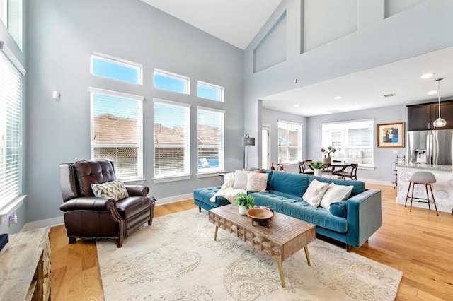 7308 Oberon St, Austin, TX 78741 - living room with light wood-style floors, a high ceiling, and baseboards