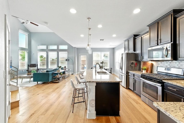 7308 Oberon St, Austin, TX 78741 - kitchen with appliances with stainless steel finishes, a sink, open floor plan, light wood-style floors, and light stone counters