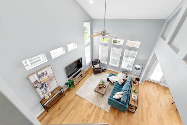 7308 Oberon St, Austin, TX 78741 - living room featuring high vaulted ceiling, wood finished floors, a glass covered fireplace, a ceiling fan, and baseboards