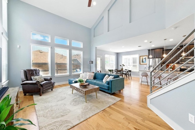 7308 Oberon St, Austin, TX 78741 - living area featuring light wood finished floors, stairs, a towering ceiling, and baseboards