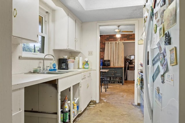 kitchen featuring a sink, white cabinetry, unfinished concrete floors, light countertops, and a ceiling fan