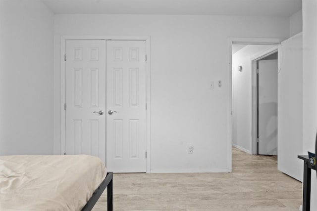 bedroom featuring light wood finished floors, a closet, and baseboards