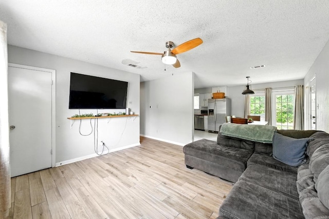 136 Shadow Oak Dr, Bastrop, TX 78602 - living room with a ceiling fan, light wood finished floors, a textured ceiling, and baseboards
