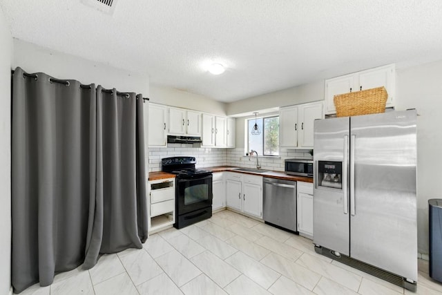 136 Shadow Oak Dr, Bastrop, TX 78602 - kitchen with appliances with stainless steel finishes, a sink, white cabinetry, wood counters, and decorative backsplash