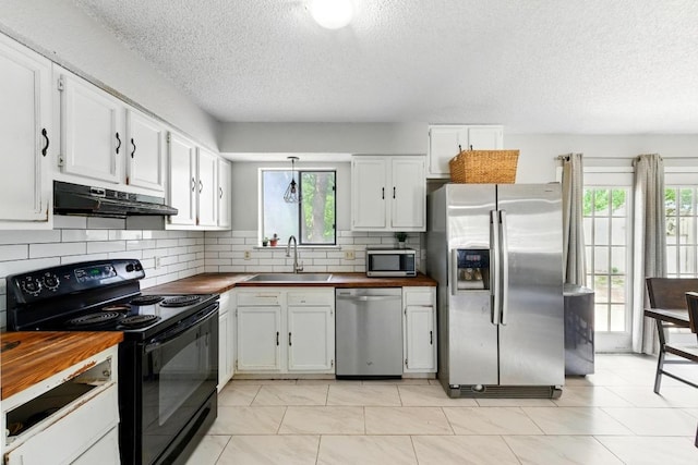 136 Shadow Oak Dr, Bastrop, TX 78602 - kitchen with appliances with stainless steel finishes, butcher block counters, under cabinet range hood, a sink, and a textured ceiling