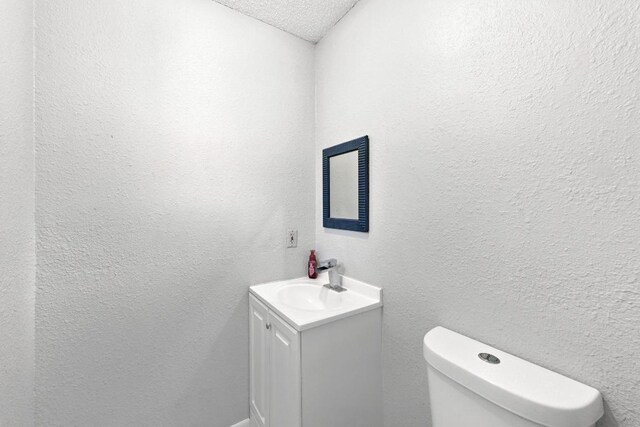 136 Shadow Oak Dr, Bastrop, TX 78602 - half bath featuring a textured wall, vanity, toilet, and a textured ceiling