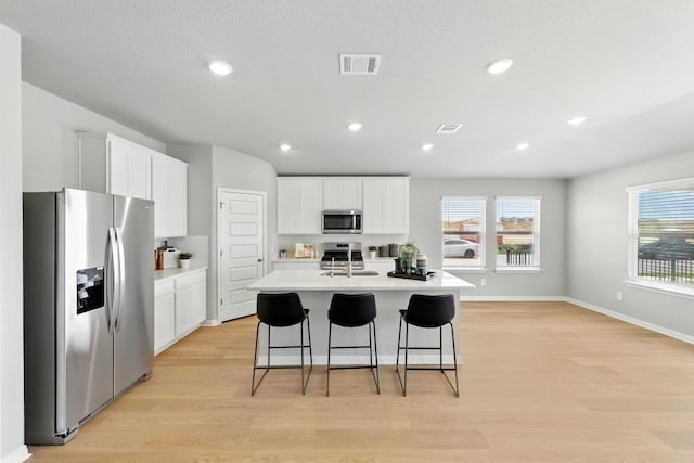 kitchen featuring stainless steel appliances, light wood-type flooring, light countertops, a sink, and healthy amount of natural light