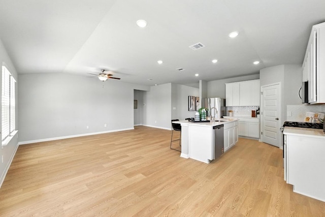 17129 Loch Rd, Pflugerville, TX 78660 - kitchen with a kitchen bar, a ceiling fan, tasteful backsplash, an island with sink, and light wood-style flooring