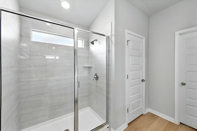 bathroom with wood finished floors, a stall shower, baseboards, and recessed lighting