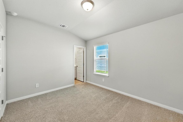 empty room with light carpet, lofted ceiling, baseboards, and a smoke detector