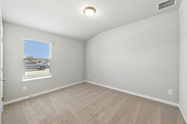 carpeted spare room with baseboards and vaulted ceiling