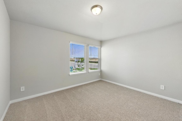 unfurnished room with carpet and baseboards
