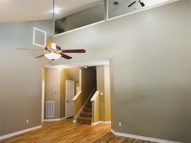 spare room featuring a ceiling fan, wood finished floors, stairway, lofted ceiling, and baseboards