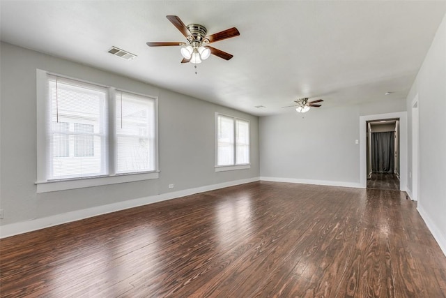 spare room featuring ceiling fan, dark wood-style floors, and baseboards
