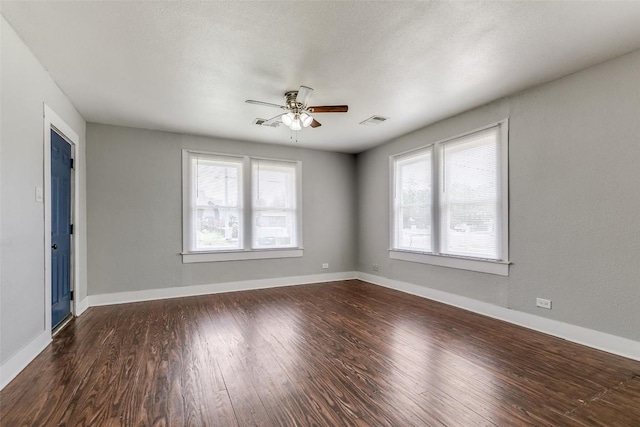 spare room featuring healthy amount of natural light, ceiling fan, dark wood-style floors, and baseboards