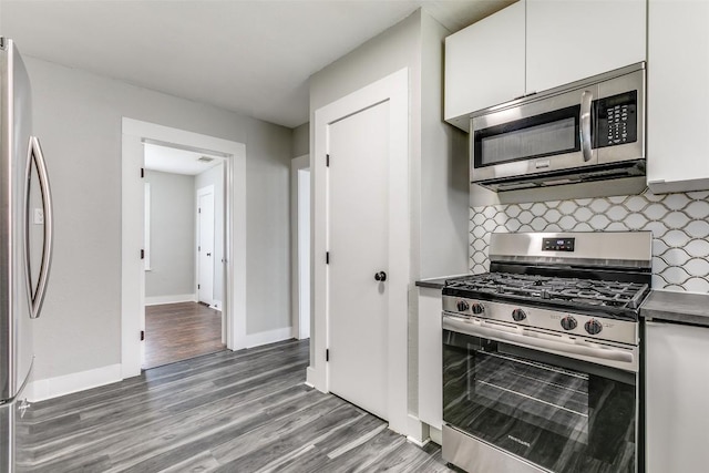 kitchen with stainless steel appliances, white cabinets, wood finished floors, and tasteful backsplash