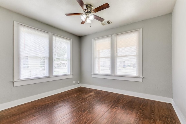 spare room with dark wood-type flooring, ceiling fan, and baseboards