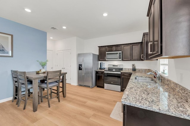 17913 Shafer Dr, Pflugerville, TX 78660 - kitchen with appliances with stainless steel finishes, a sink, dark brown cabinetry, light wood-type flooring, and recessed lighting