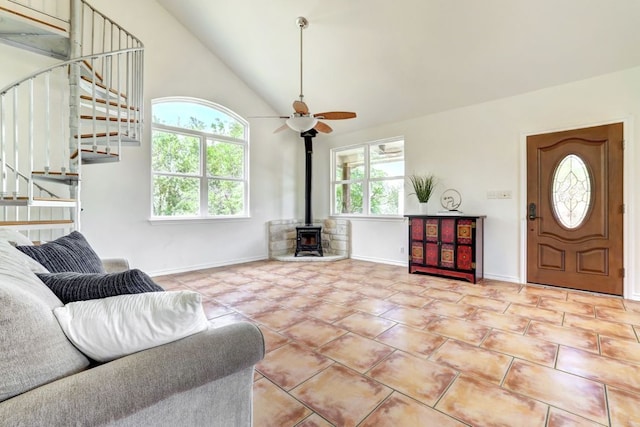 195 Live Oak, Liberty Hill, TX 78642 - tiled living room featuring a wood stove, stairway, a ceiling fan, baseboards, and high vaulted ceiling