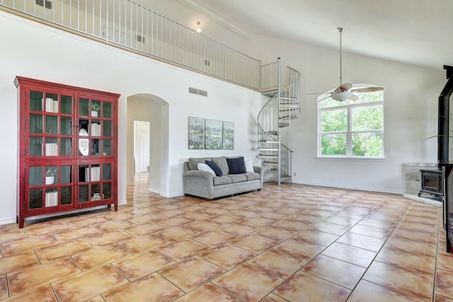 195 Live Oak, Liberty Hill, TX 78642 - living room featuring arched walkways, a wood stove, a ceiling fan, stairway, and high vaulted ceiling