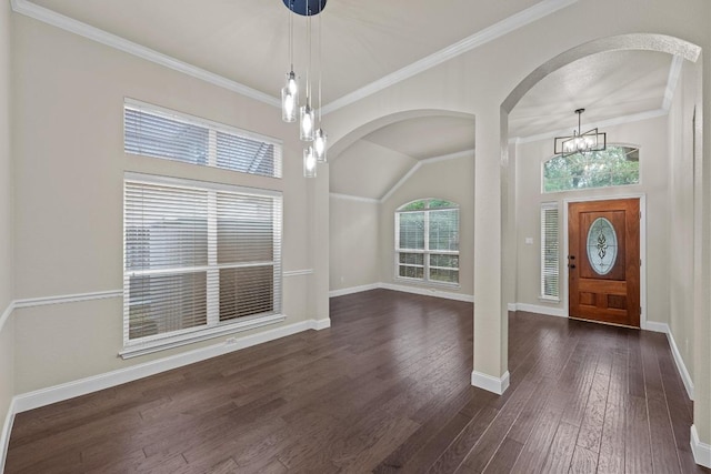 entrance foyer with dark wood-style floors, a chandelier, baseboards, arched walkways, and ornamental molding