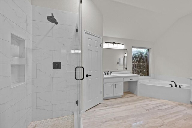 full bath featuring a stall shower, a garden tub, vanity, and vaulted ceiling