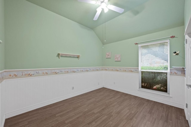 spare room with wood finished floors, ceiling fan, lofted ceiling, and a wainscoted wall