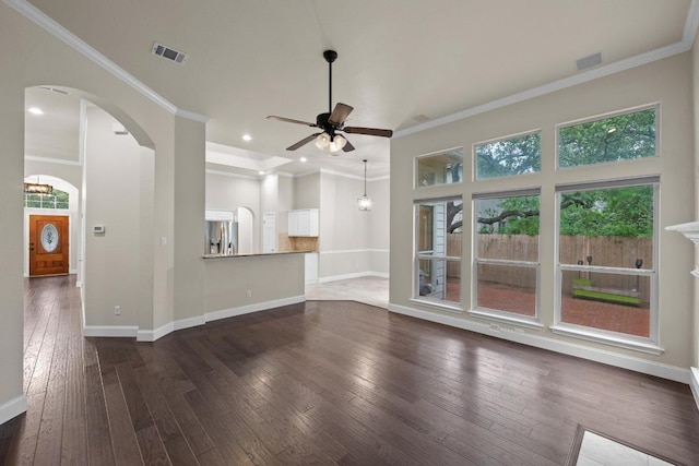 unfurnished living room featuring arched walkways, ceiling fan, dark wood finished floors, baseboards, and ornamental molding