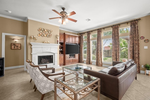 living room featuring baseboards, crown molding, light tile patterned floors, ceiling fan, and a fireplace with raised hearth