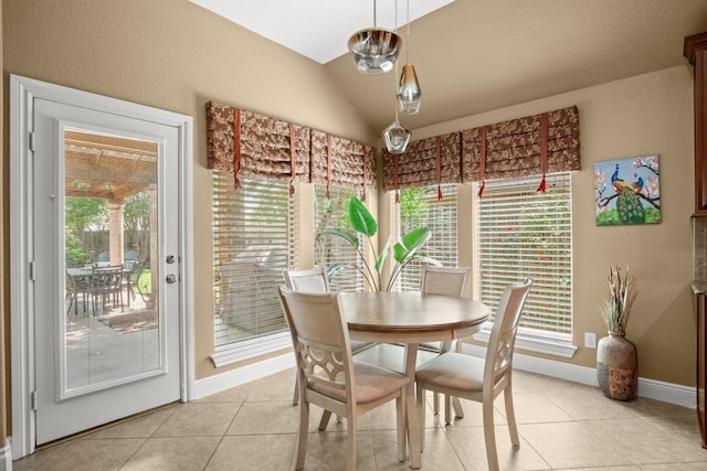dining room featuring light tile patterned flooring, healthy amount of natural light, vaulted ceiling, and baseboards