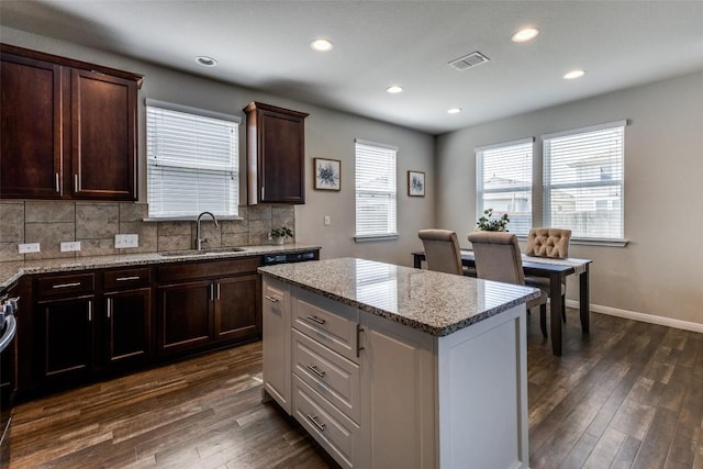 kitchen with a sink, dark wood-type flooring, tasteful backsplash, light stone counters, and recessed lighting