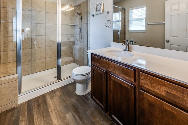 full bathroom featuring a shower stall, wood finished floors, toilet, and vanity