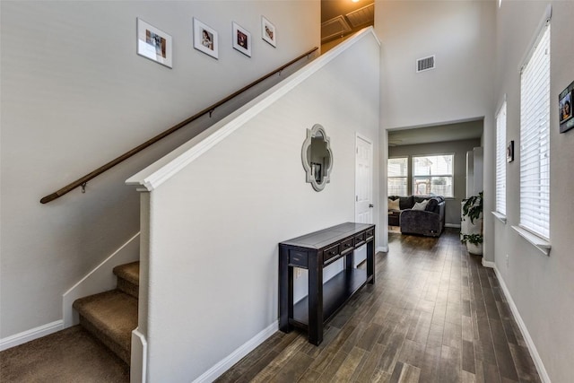 stairs featuring a high ceiling, wood finished floors, and baseboards