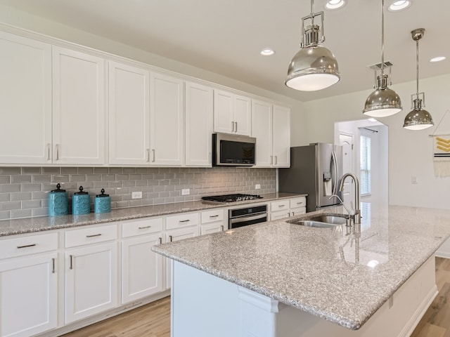 4325 Arques Ave, Round Rock, TX 78681 - kitchen featuring stainless steel appliances, a sink, light wood-type flooring, a center island with sink, and white cabinetry