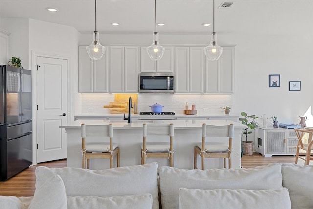 424 Turnbuckle Bnd, Leander, TX 78641 - kitchen featuring freestanding refrigerator, stainless steel microwave, open floor plan, light wood-style floors, and recessed lighting