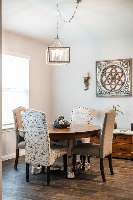 dining space with a chandelier, dark wood-type flooring, and baseboards