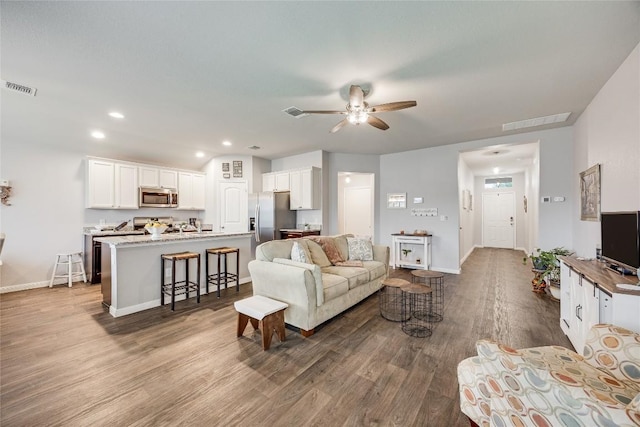 living area featuring dark wood finished floors, a ceiling fan, baseboards, and recessed lighting
